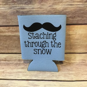 May include: A light blue can cooler with a black mustache and the text "Staching through the snow".