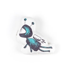 Peut inclure: Jouet en peluche blanc en forme d'astronaute de dessin animé avec des détails bleus et noirs. L'astronaute porte un casque et a un jetpack.