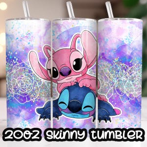 Op de afbeelding: Een witte slanke tumbler met een roze en blauwe Stitch en Angel ontwerp. De achtergrond is een aquarel-achtig ontwerp met paarse en blauwe tinten en glitter accenten.