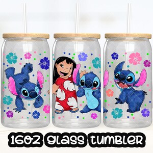 May include: Three 16oz glass tumblers with a wood lid and straw. Each tumbler features a different design with Stitch and Lilo from the Disney movie Lilo & Stitch. The designs include Stitch with pink ears, Stitch with blue ears, and Lilo with Stitch.