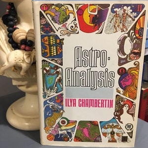 Könnte beinhalten: Ein Vintage-Buch mit dem Titel "Astro-Analysis" von Ilya Chambertin. Der Umschlag zeigt ein farbenfrohes Design mit astrologischen Symbolen und Illustrationen.