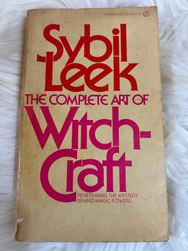 May include: Vintage paperback book titled "Sybil Leek: The Complete Art of Witchcraft." The cover features bold red and pink lettering on a tan background. The book promises to reveal the mystery behind magic powers.