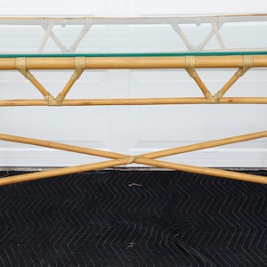May include: A rectangular bamboo console table with a glass top. The table has a natural wood finish and a simple, elegant design.