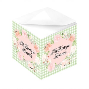 Könnte beinhalten: Ein grünes und weißes karierter Notizblock mit einem Blumendesign und dem Namen "Kenzie Barnes" in Kursivschrift. Der Notizblock hat ein rosafarbenes Blumendesign mit rosafarbenem Hintergrund.