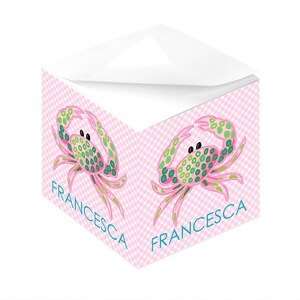 May include: Pink and white gingham notepad with a green and pink crab design. The notepad has the name "Francesca" printed on it.
