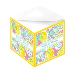 May include: A yellow notepad with a pink background and a lemon pattern. The notepad has a yellow border and the name "Bethany Morris" is printed on the front.