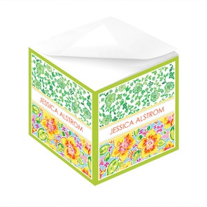 Könnte beinhalten: Ein grüner, würfelförmiger Notizblock mit einem Blumendesign. Die Oberseite des Notizblocks ist weiß und die Vorderseite des Notizblocks hat einen grünen Rand. Der Text "JESSICA ALSTROM" ist auf der Vorderseite des Notizblocks gedruckt.