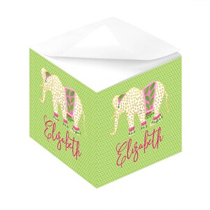 以下が含まれることがあります： 白の上部に緑色のメモ帳で、金と白の象のデザインが施されています。象はピンクと緑の模様の入ったスカートを履いています。メモ帳には、ピンクで「エリザベス」という名前が書かれています。