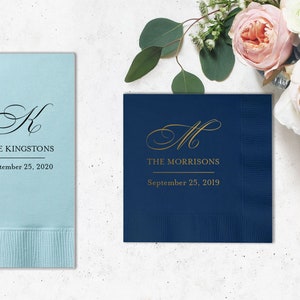 Pode incluir: Duas toalhas de mesa personalizadas, uma azul claro com um "K" preto e o texto "THE KINGSTONS September 25, 2020", e uma azul marinho com um "M" dourado e o texto "THE MORRISONS September 25, 2019".