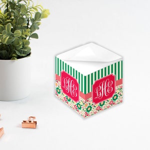 May include: A green and white striped notepad with a floral design and a red monogram "LHE" on the front. The notepad is sitting on a white surface.
