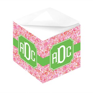 May include: A pink and white floral patterned notepad with a green ribbon and a green monogram that says "ADC".