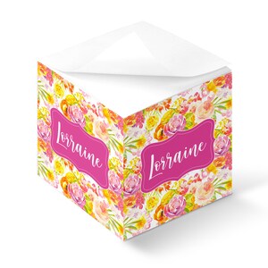 May include: A pink floral notepad with the name "Lorraine" written in white script on a pink banner. The notepad has a white top and is filled with lined paper.