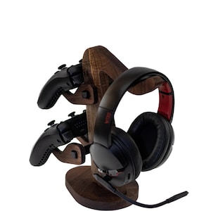 May include: A wooden stand with a headset and two controllers. The stand is made of dark wood and has a tree-like shape. The headset is black with red accents and a microphone. The controllers are black and have a textured grip.