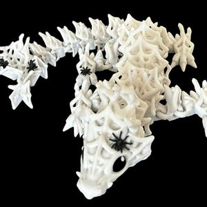 May include: White plastic spider web sculpture with black spiders. The sculpture is made of interlocking pieces that form a web-like design.