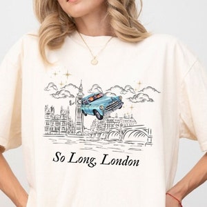May include: A white t-shirt with a black and white illustration of a car flying over a cityscape with the text "So Long London".