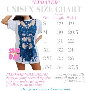May include: White unisex t-shirt with a blue and beige design. The image includes a size chart with measurements in inches for sizes S to 3XL. The text on the shirt says "SUNDAY".