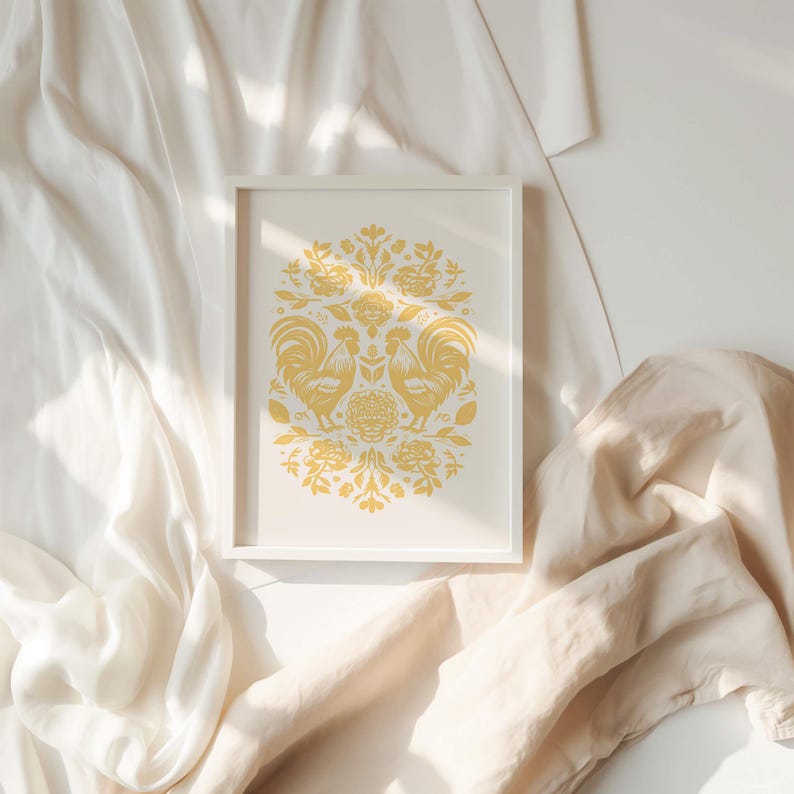 A framed November birth flower art print featuring two stylized green birds and intricate floral patterns is placed on a soft, cream-colored fabric background with gentle folds and light streaming in from one side.