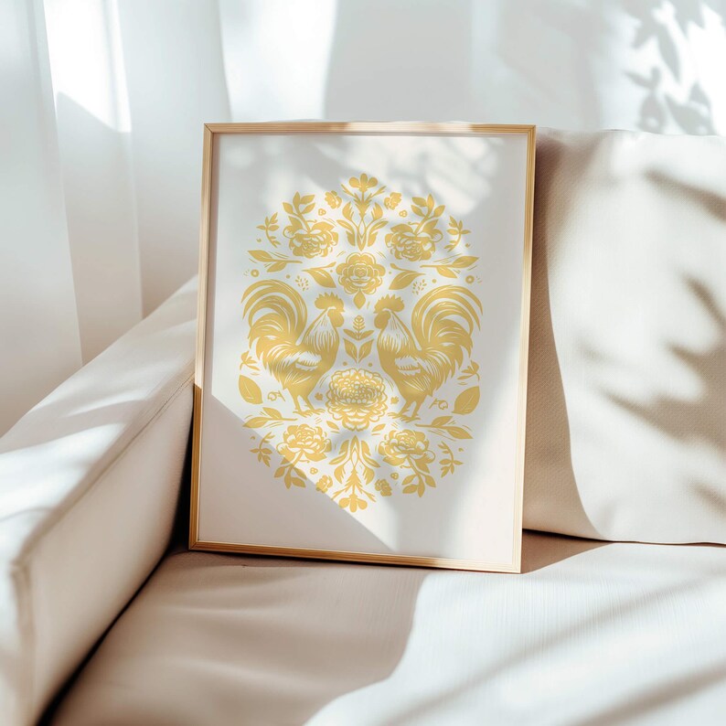 A framed artwork featuring a symmetrical design with two birds facing each other, surrounded by flowers, leaves, and intricate patterns. The piece rests on a light-colored cushioned sofa in a bright room. This November birthday gift exudes charm.