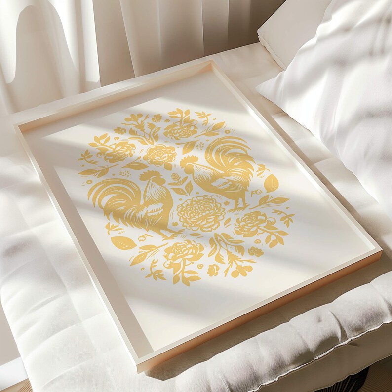 A framed artwork of two symmetrical birds surrounded by various floral and nature-inspired motifs is placed on a white cushioned surface. The handmade gift, set in bright sunlight casting soft shadows, has a backdrop of pleated white curtains.