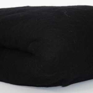 May include: A folded, black textile item, possibly fabric or a finished product. The material appears soft and textured, with a slightly irregular shape. The item is set against a plain white background, highlighting its dark color and form.