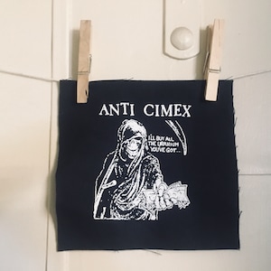 May include: Black fabric patch with the words "ANTI CIMEX" in white block letters. A white illustration depicts a hooded figure holding money and a scythe, with the text "I'll buy all the uranium you've got..."
