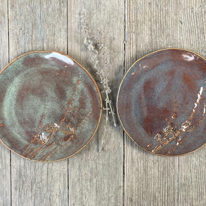 May include: Two ceramic plates with a brown and green glaze. The plates have a rustic, handmade look.