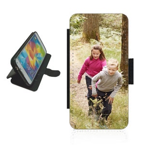 Może przedstawiać: Czarne etui na telefon z fotografią dwojga dzieci idących po lesie. Na zdjęciu widać dziewczynkę w różowej koszulce i chłopca w szarej koszulce.