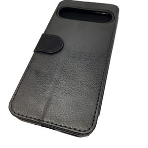 May include: Black leather phone case with a flap that covers the screen. The case has a textured surface and a stitched edge.