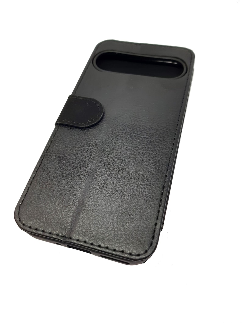 May include: Black leather phone case with a flap that covers the screen. The case has a textured surface and a stitched edge.