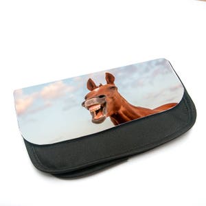 Op de afbeelding: Een zwarte etui met rits met een bedrukte afbeelding van een bruin paard met zijn mond open, zijn tanden zichtbaar, tegen een blauwe lucht met witte wolken.