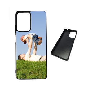 May include: A black phone case featuring a photograph of a father and son playing in a grassy field. The father is holding the son aloft, and the son is smiling. The sky is blue with clouds.