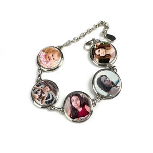 May include: A silver charm bracelet with five round photo charms. Each charm features a different photo of a person. The bracelet is on a white background.