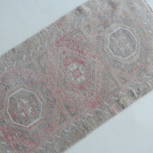 May include: A vintage rug with a faded red and gray pattern. The rug has a geometric design with repeating octagons and diamond shapes.