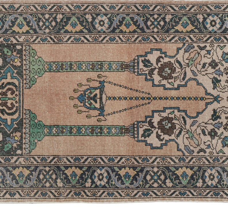 May include: A beige prayer rug with a traditional design featuring a central chandelier motif and floral patterns in shades of blue, green, and brown. The rug has a border with intricate geometric designs.
