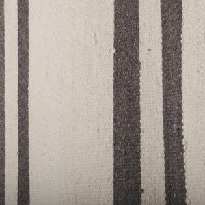 May include: A white rug with two dark brown stripes running vertically down the length of the rug.