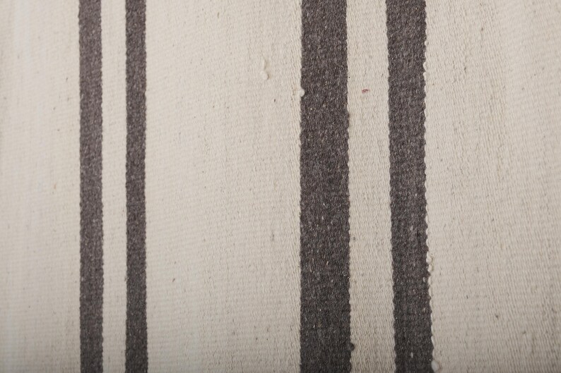 May include: A white rug with two dark brown stripes running vertically down the length of the rug.