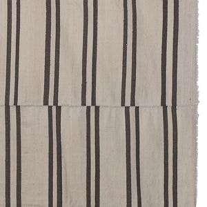 May include: A white and black striped rug with a woven texture. The rug has a fringe border.