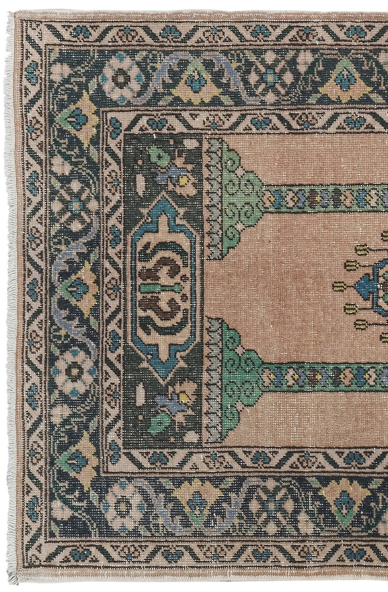 May include: A vintage rug with a beige background and a dark blue, green, and cream patterned border. The rug has a traditional design with floral motifs and geometric shapes.