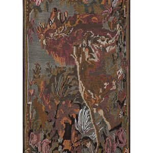 Op de afbeelding: Een rechthoekige wandtapijt met een gedetailleerd ontwerp met een leeuw, bloemen en bladeren in tinten bruin, rood, groen en grijs. Het wandtapijt heeft een donkere rand en een gefranjerde rand, geschikt voor wanddecoratie.