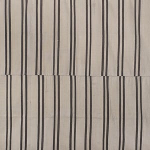 May include: A white and black striped rug with a woven texture. The rug has a simple design with vertical stripes.