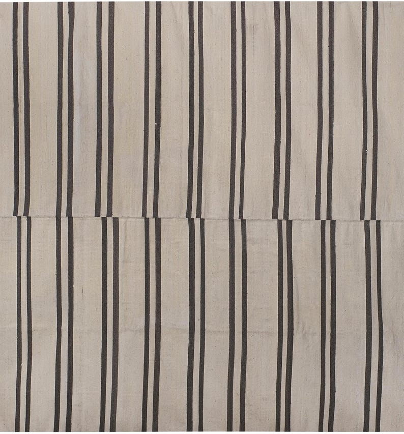 May include: A white and black striped rug with a woven texture. The rug has a simple design with vertical stripes.
