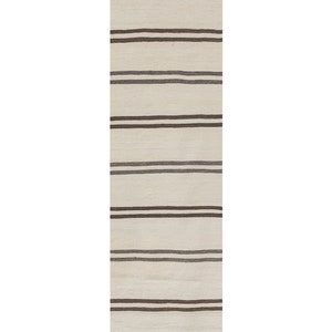 May include: A rectangular, cream-colored rug with horizontal stripes in varying shades of brown. The rug has a fringed edge and is suitable for a hallway or entryway. The rug's dimensions are not visible.