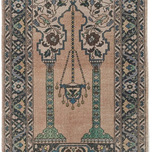 May include: A traditional prayer rug with a beige background and a blue, green, and cream floral pattern. The rug features a central archway with a hanging lamp and two pillars.