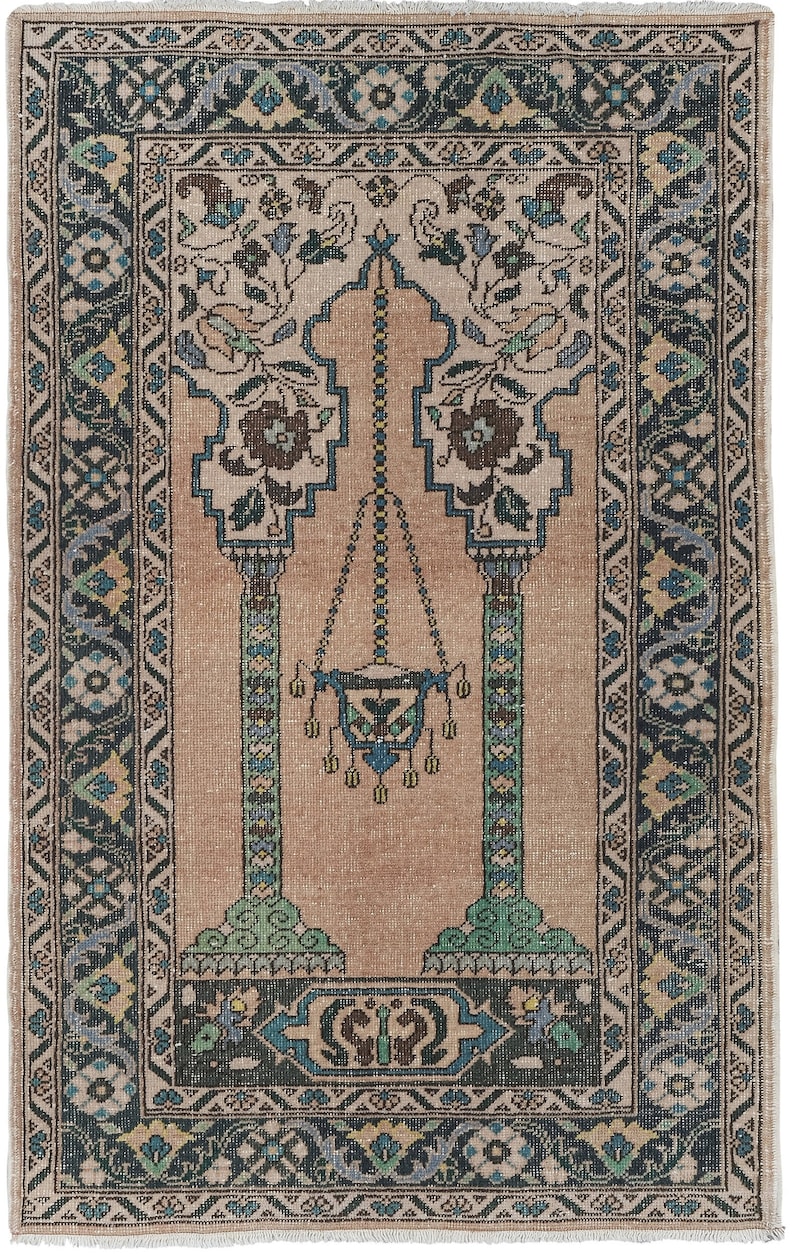 May include: A traditional prayer rug with a beige background and a blue, green, and cream floral pattern. The rug features a central archway with a hanging lamp and two pillars.