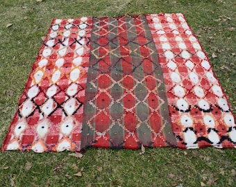 Peut inclure: Un tapis rouge, blanc et noir à motifs en forme de losange. Le tapis est en laine et a une texture tissée à la main.