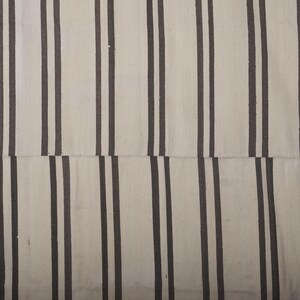 May include: A white and black striped rug with a woven texture. The rug has a simple design with alternating stripes of white and black.