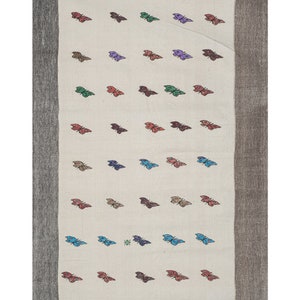 May include: A white rug with a brown border features a repeating pattern of colorful butterflies. The butterflies are in various shades of red, blue, green, purple, and orange.