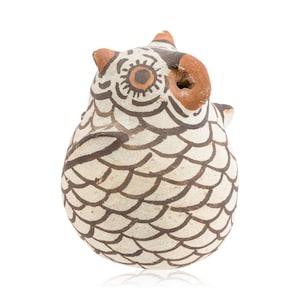 May include: A small, white ceramic owl with brown and orange painted details. The owl has a round body with a scaly pattern and a small beak with a hole in the top.