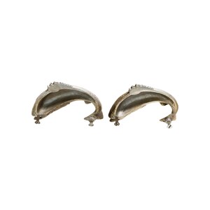May include: Two antique silver-toned cabinet handles. Each handle has a curved, shell-like design with a textured surface and decorative edge. The handles are mounted with screws for easy installation. Ideal for furniture restoration or adding vintage charm.