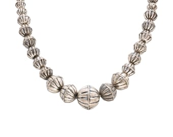 May include: A silver necklace with round, textured beads. The necklace has a larger, round bead in the center.